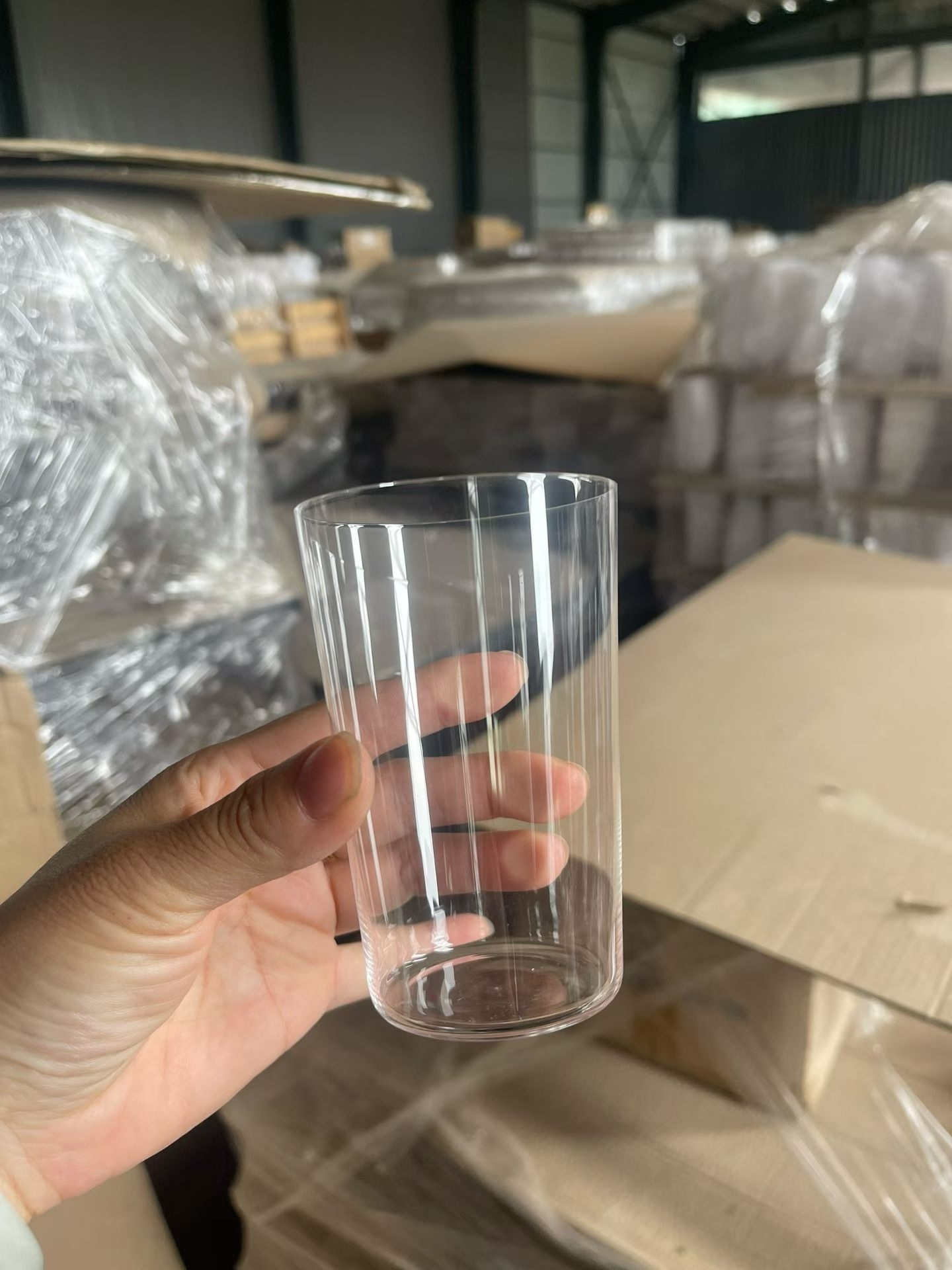 crystal glass slim tumbler held up with packed cartons behind